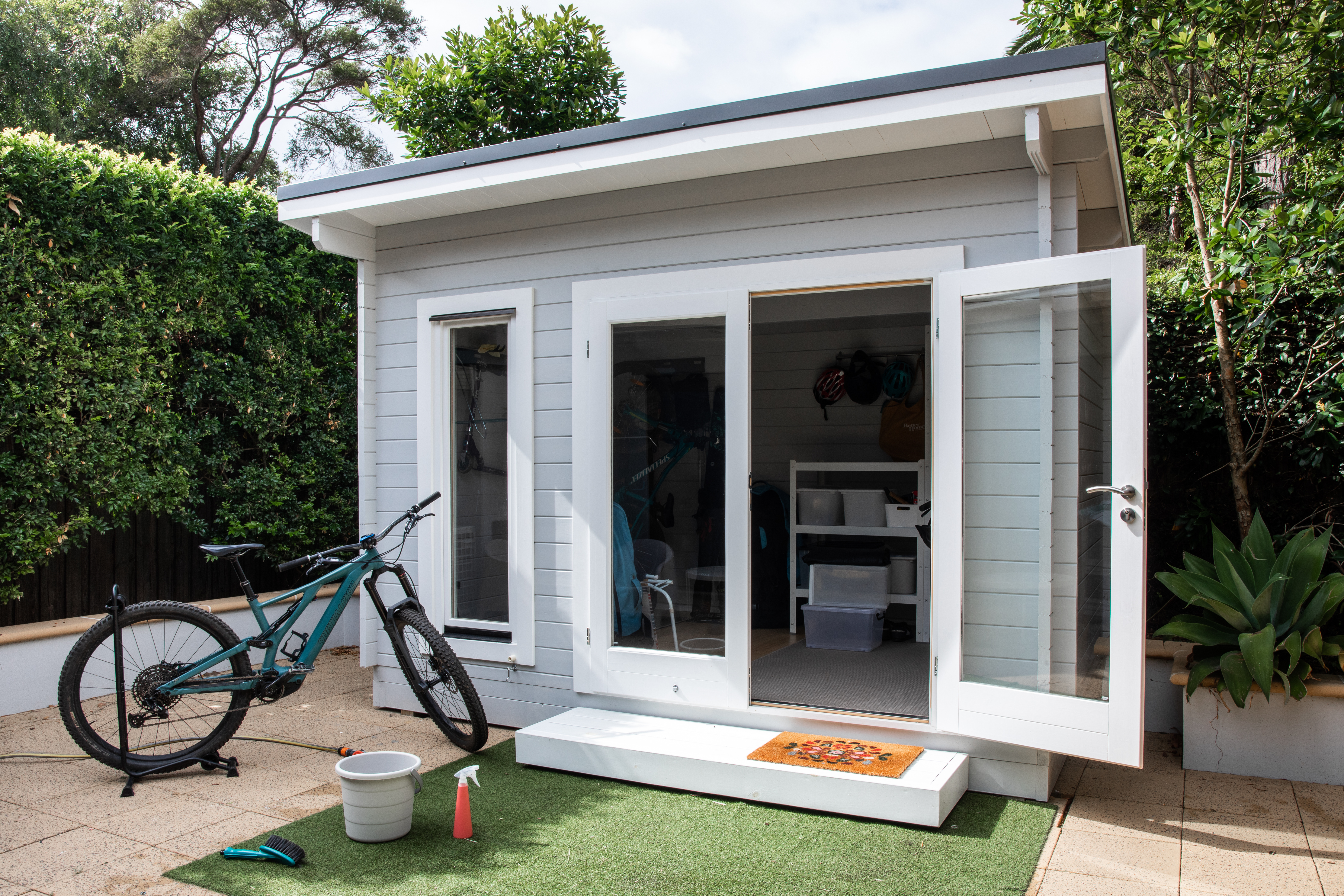 a small housing unit grey with white trim and a bicycle parked in the front