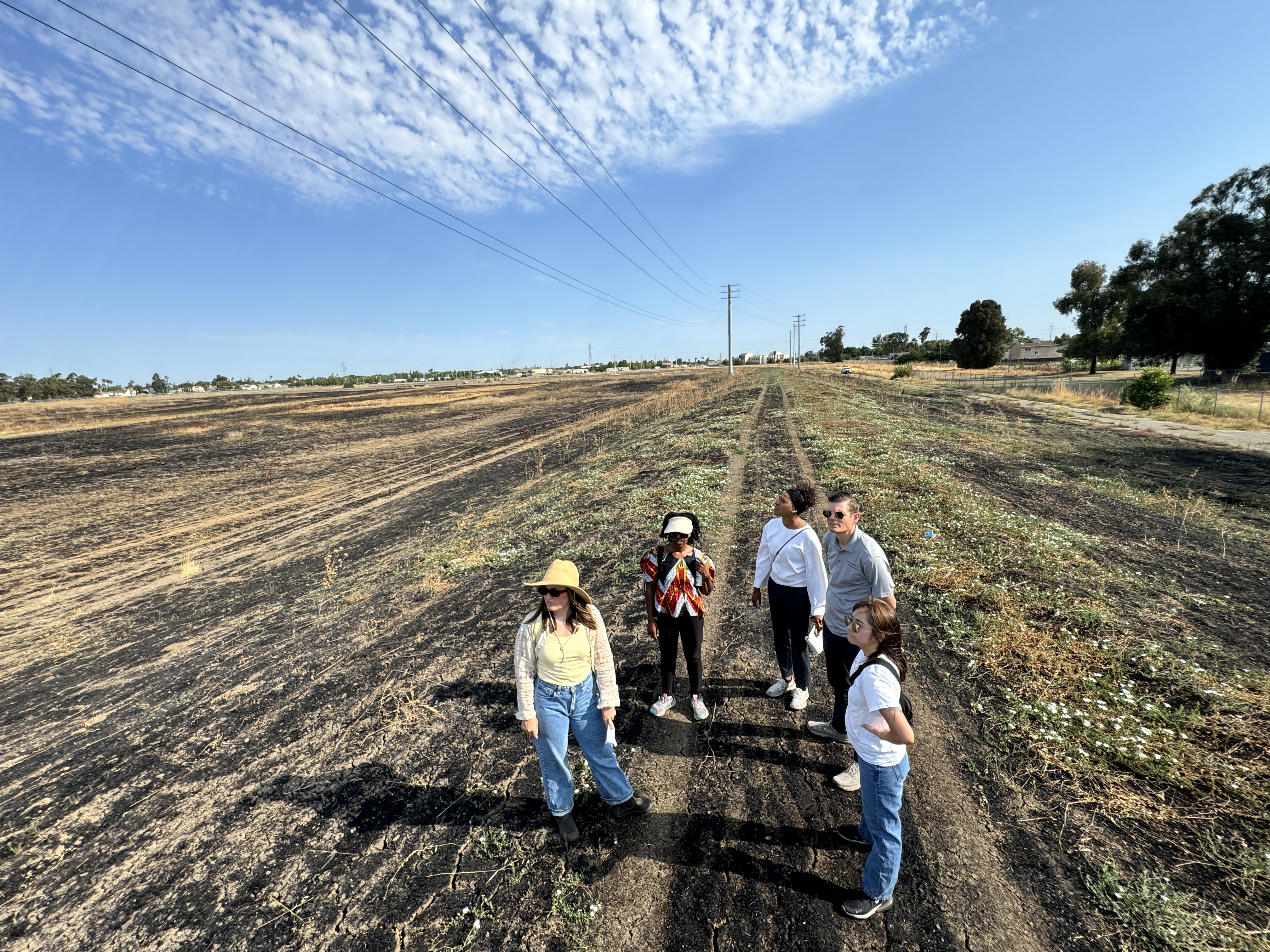 five people standing on open land, blue skies
