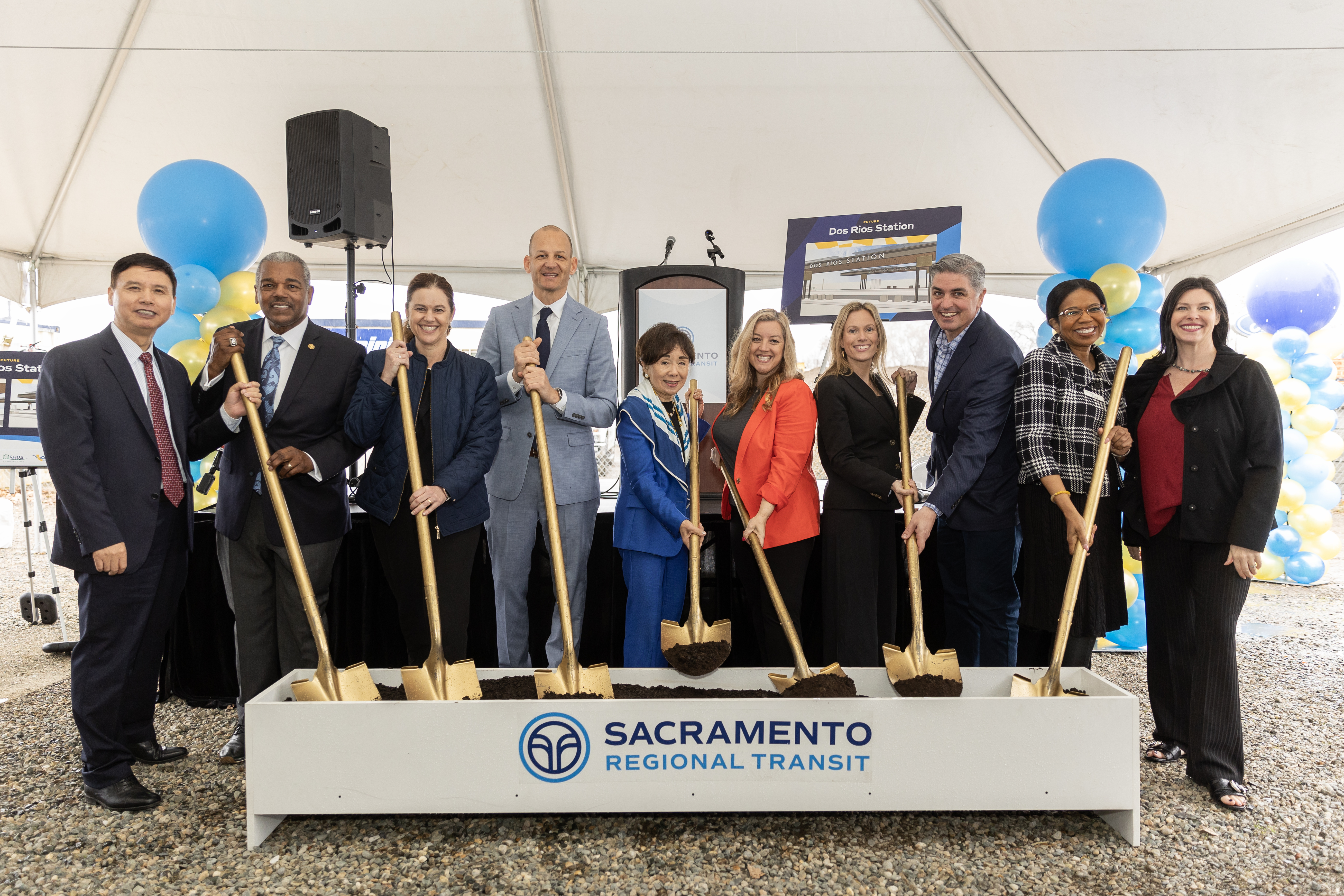 Dos Rios ground breaking photo with 10 people holding shovels with Sacramento Regional Transit logo on box of dirt