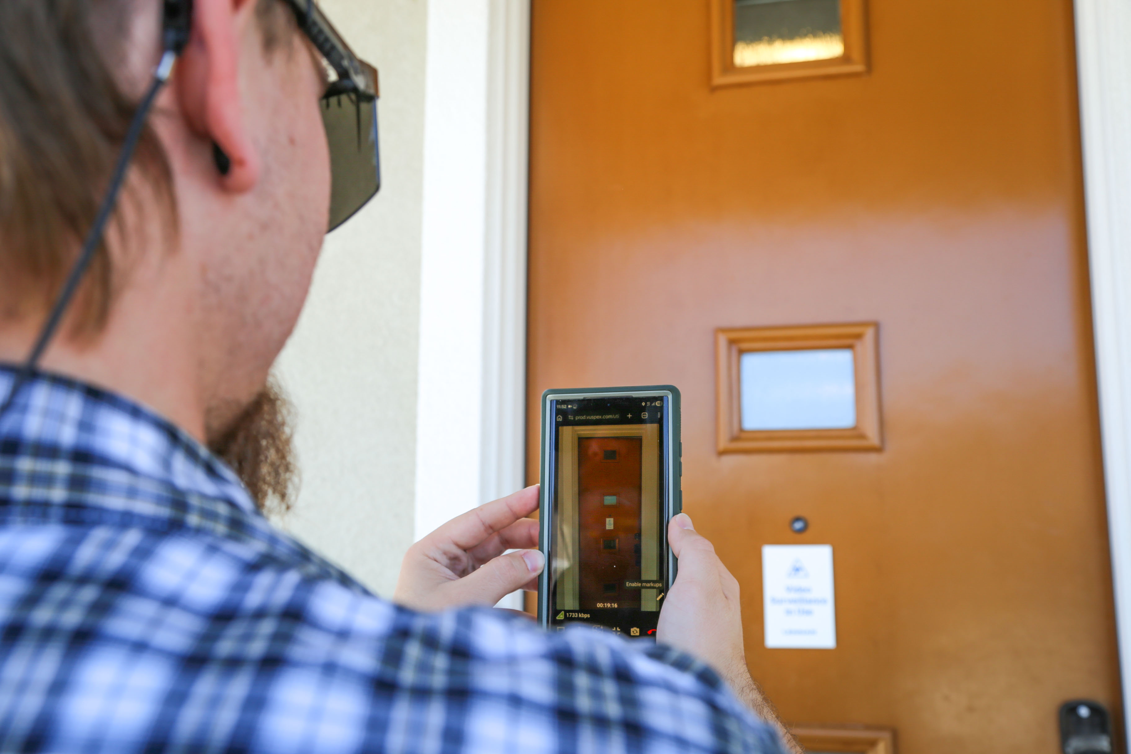 close up over the shoulder of a person holding a smart device looking at a door